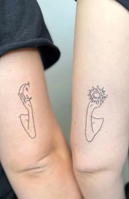 Minimalist matching tattoos of hands holding the sun and moon on forearms