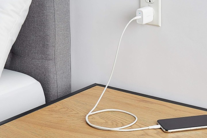 Amazon Basics 30W One-Port GaN USB-C Charger plugged in next to a table where phone is being charged.