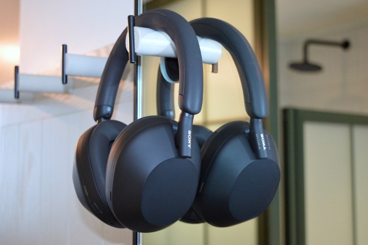 The Sony WH-1000XM5 wireless headphones hang on a wall hook in front of the mirror.