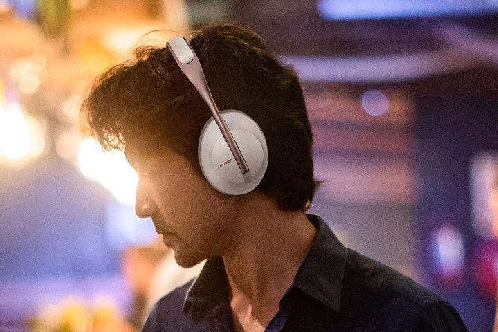 A man wearing Bose 700 headphones against a moody background.