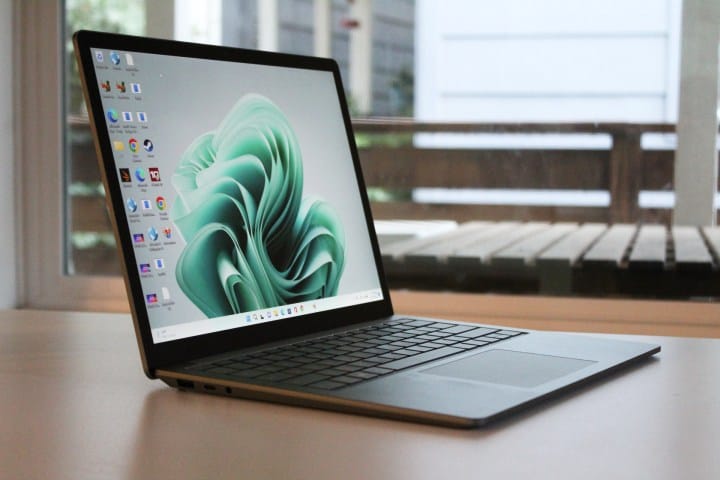 The Surface Laptop 5 is on a table in front of a window.