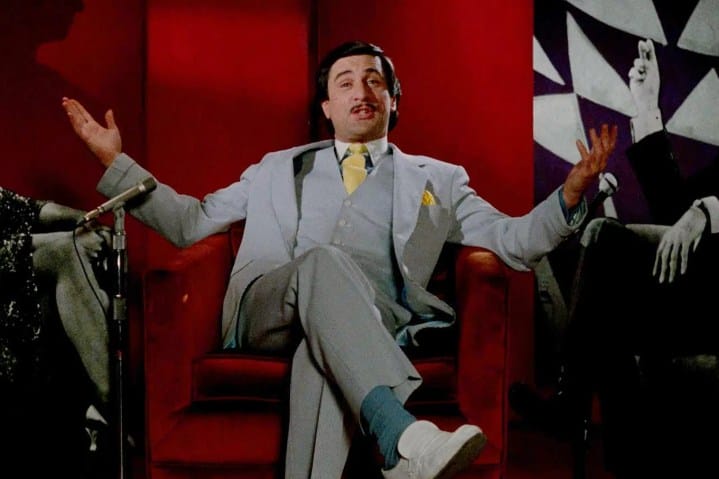 Robert De Niro sitting on a red chair in The King of Comedy.