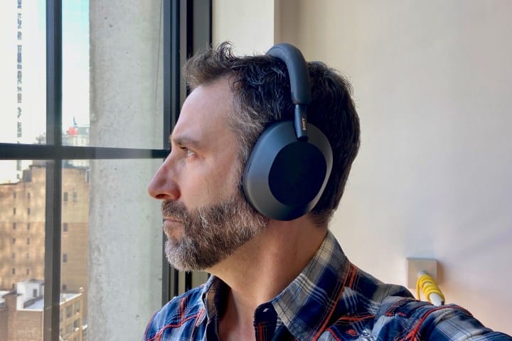 Side view of a person wearing Sony WH-1000XM5 wireless headphones.