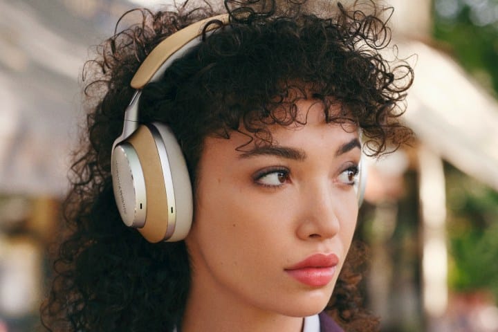 Woman wearing B&W Px8 wireless headphones in tan.