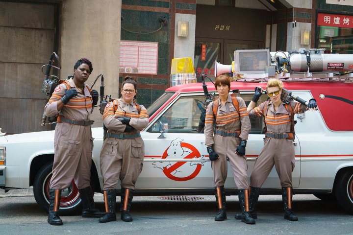 Four female ghosts are standing in front of a car.