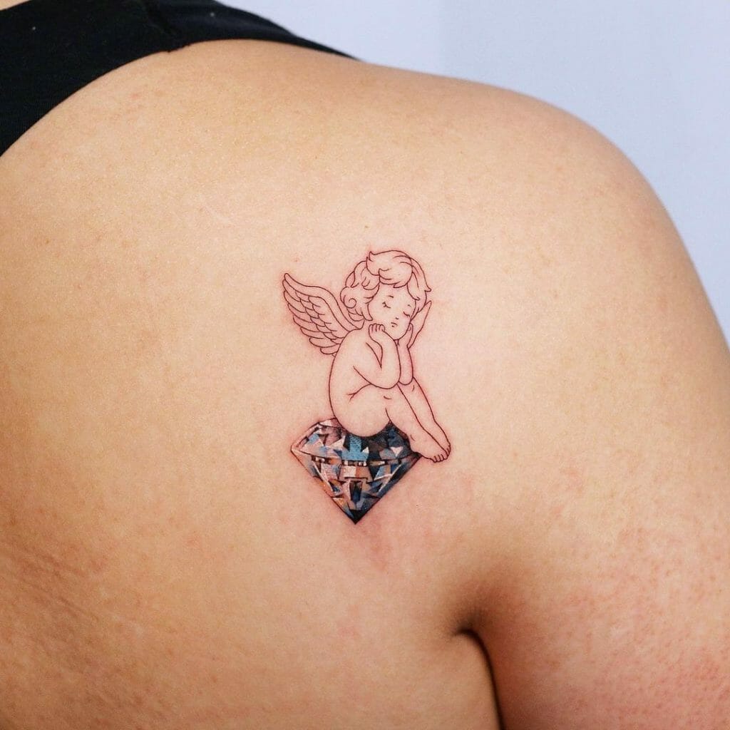 Baby angel tattoo sitting on a diamond