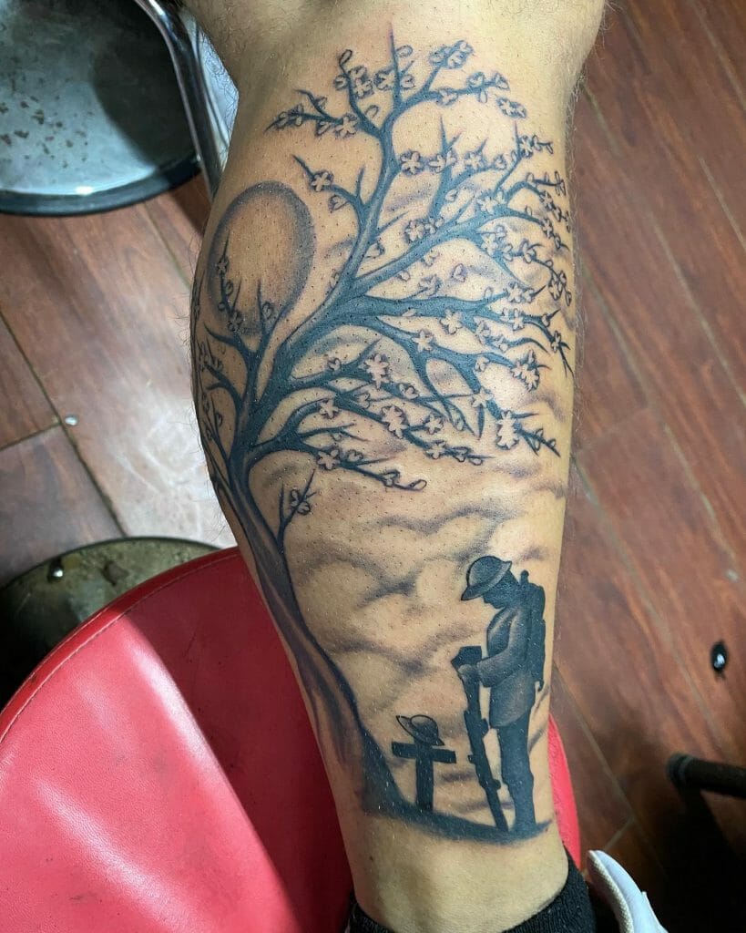 Silhouette of a fallen soldier memorial tattoo under a blossoming tree with a sunset in the background, located on the calf