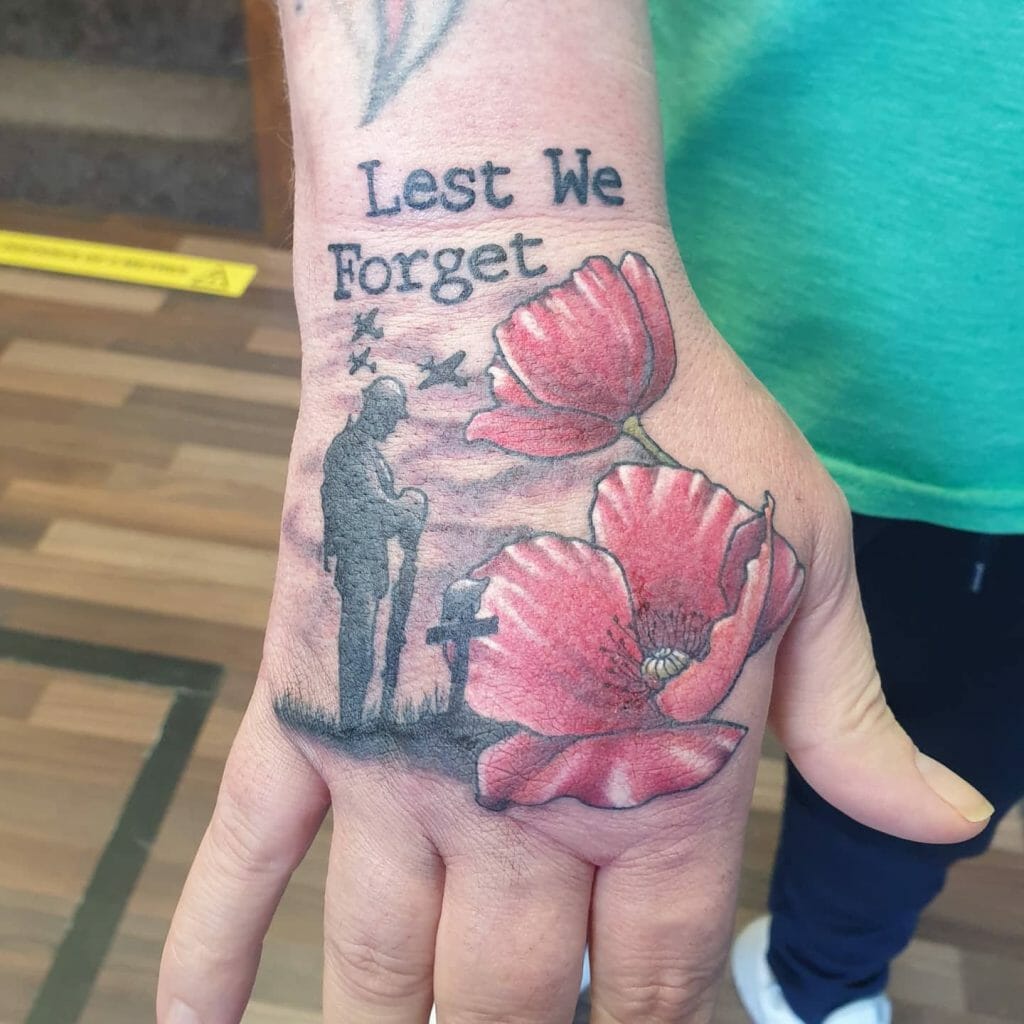 Hand tattoo featuring the text 'Lest We Forget,' red poppies, a fallen soldier memorial silhouette, and planes in the sky