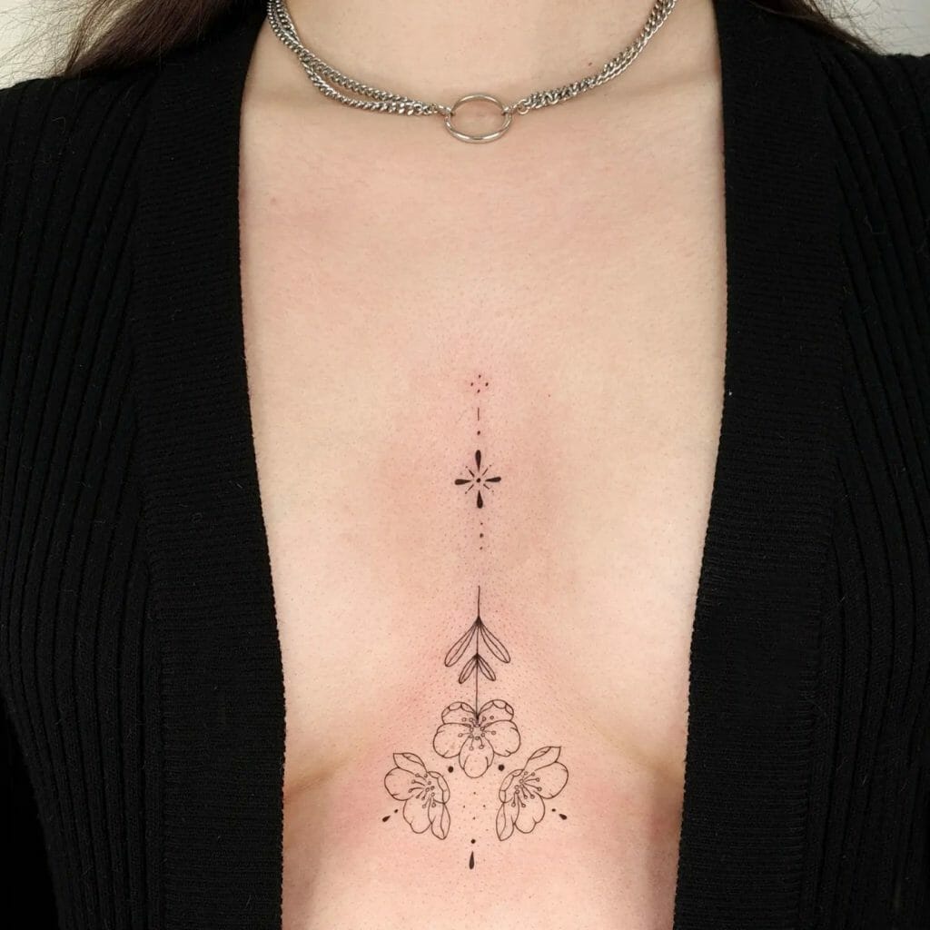 Minimalist floral under-breast tattoo with delicate line work and dot accents, featuring symmetrical floral and leaf elements