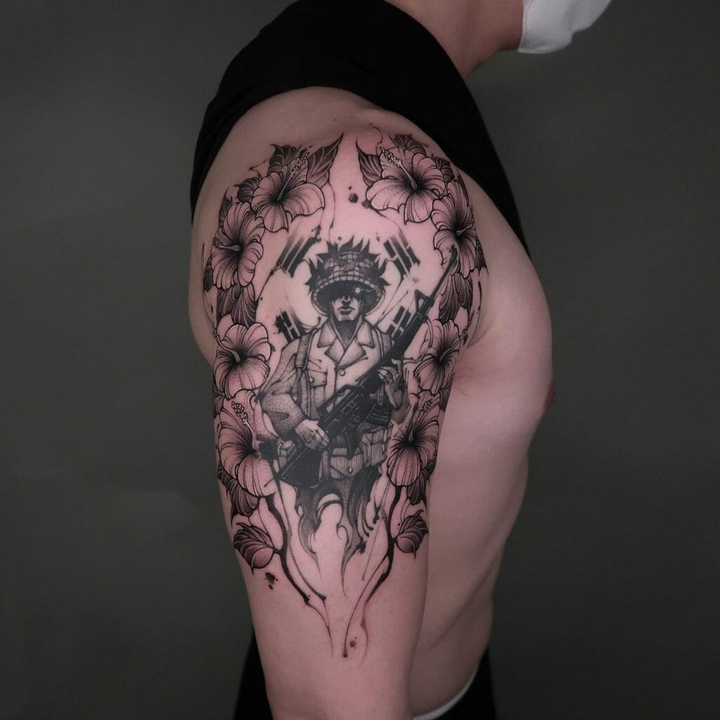 Black and grey tattoo of a modern soldier holding a rifle, surrounded by floral designs on the upper arm