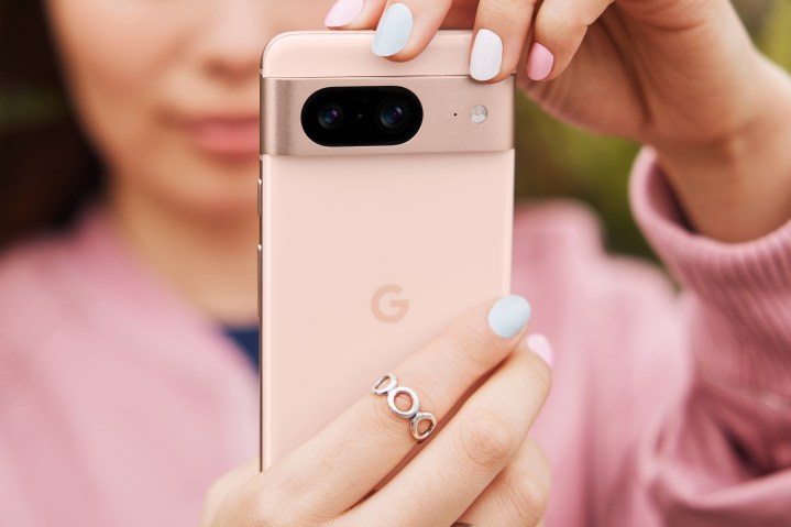 Someone is holding a pink Google Pixel 8, while also wearing a pink shirt.