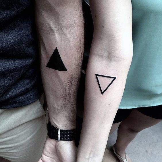 Minimalist matching triangle tattoos for couples, filled and outlined on each partner’s forearm