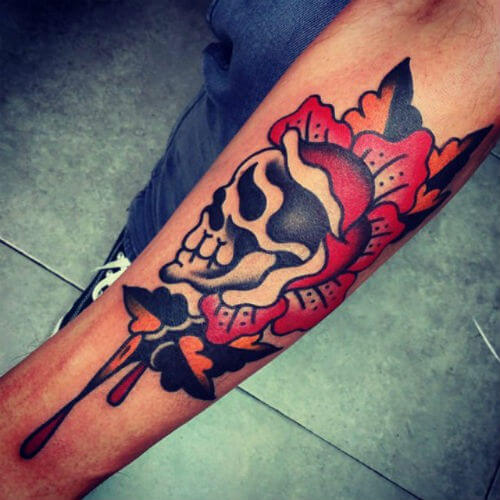 Traditional style skull and rose tattoo on forearm with bold black and red colors