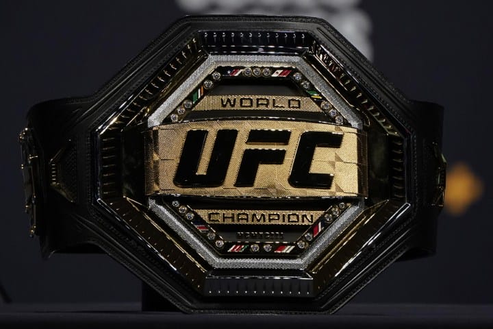 A UFC championship belt rests on a table.