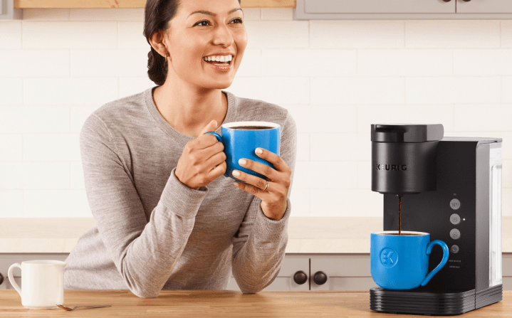 A woman sitting next to a Keurig K-Express coffee maker.