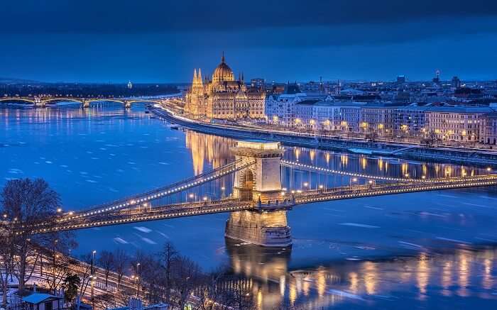 well lit Budapest parliament and bridge at night 