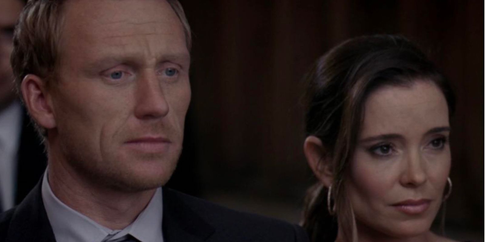 Owen and Emma looking serious attending a wedding in Grey's Anatomy