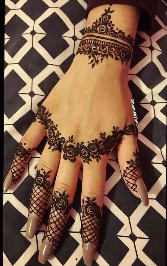 Elegant backhand Mehndi design featuring lace-like patterns and rose motifs around the wrist and fingers