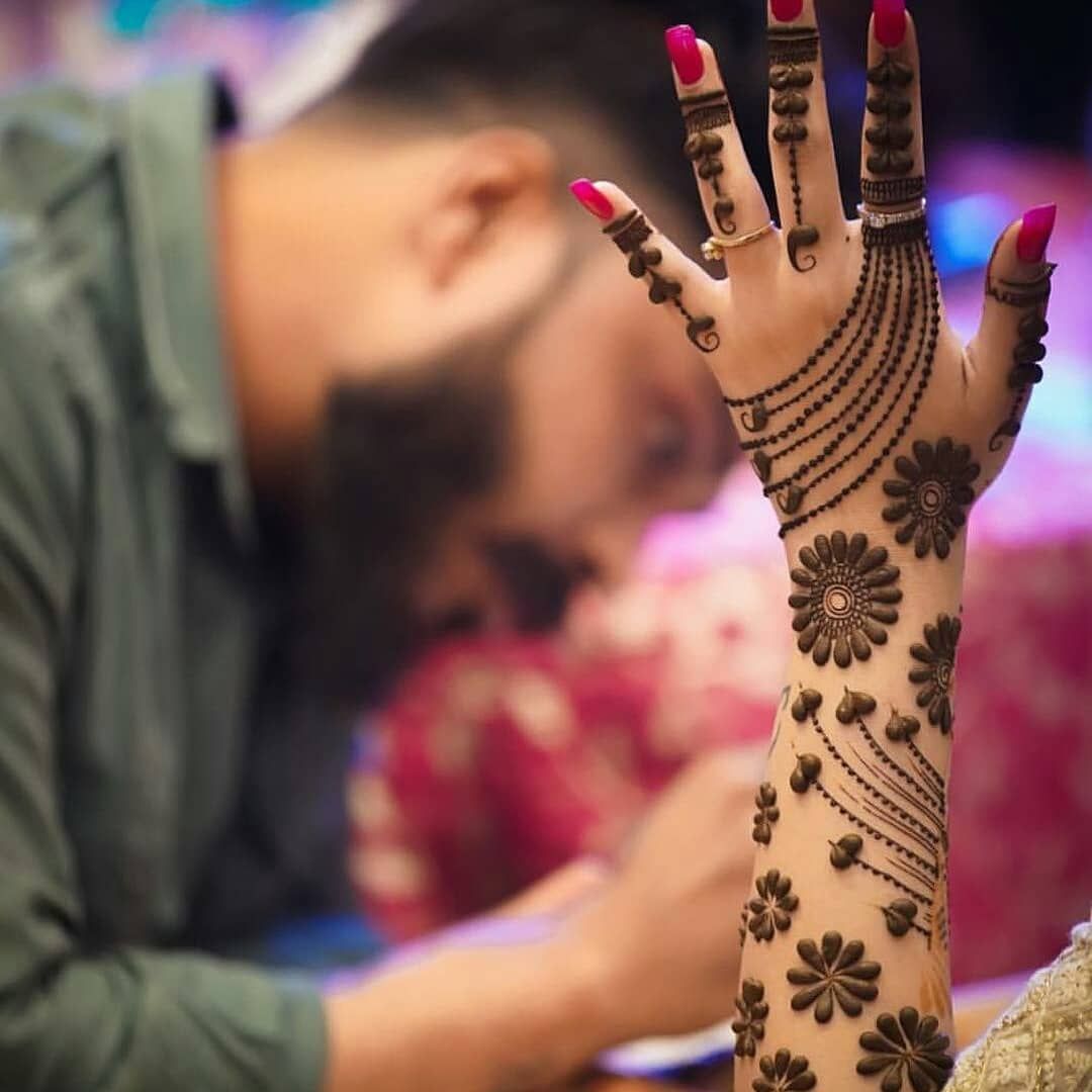 Floral Mehndi design featuring bold circular motifs and geometric detailing on the wrist and fingers, ideal for festive occasions