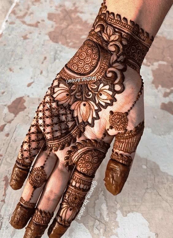 Intricate floral and geometric Mehndi design on the back of the hand with bold patterns and fine detailing