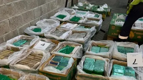 NCA A police image showing packets of cocaine carefully packaged with green and white cellophane and inside a row of banana crates 