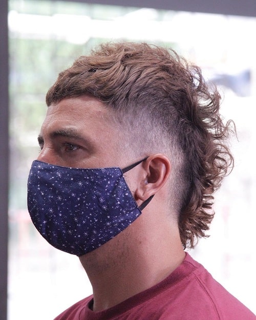 Side view of a man with a spiked mullet haircut and high fade, featuring textured top spikes and short sides