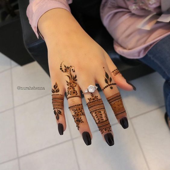 An intricate Mehndi design with floral motifs and ornate bands covering the fingers, paired with elegant swirls and leaf patterns extending onto the back of the hand