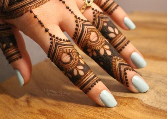 A geometric and floral Mehndi design on the fingers, featuring intricate detailing with bold lines and filled petals