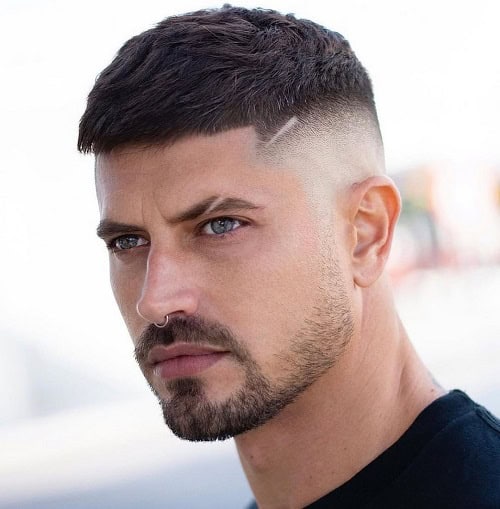 Man with a faded crew cut hairstyle featuring a clean fade and a sharp side design, wearing a black t-shirt.