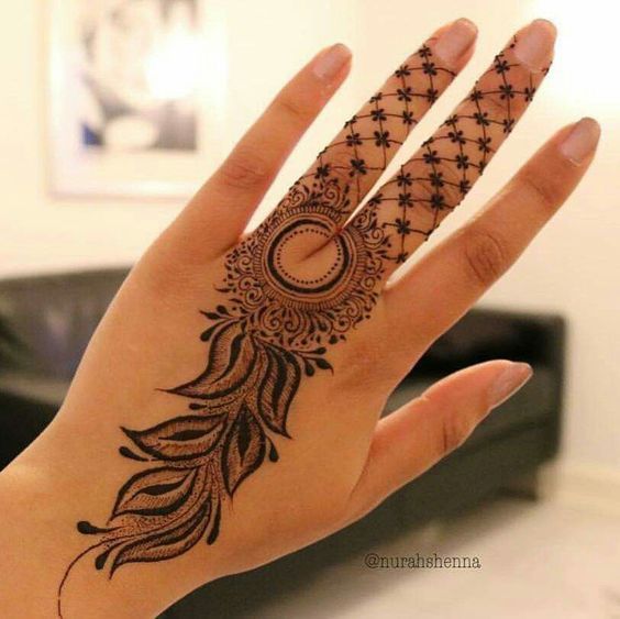 A delicate Mehndi design featuring a circular mandala with intricate leaf and floral patterns extending down the hand, and star-like motifs on the fingers