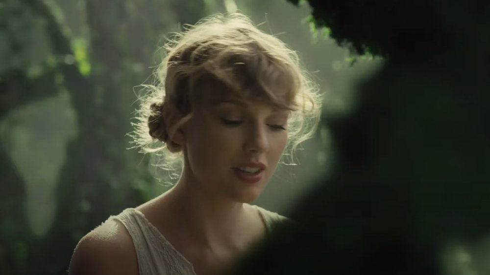 Taylor Swift wearing a cardigan in a whimsical forest setting