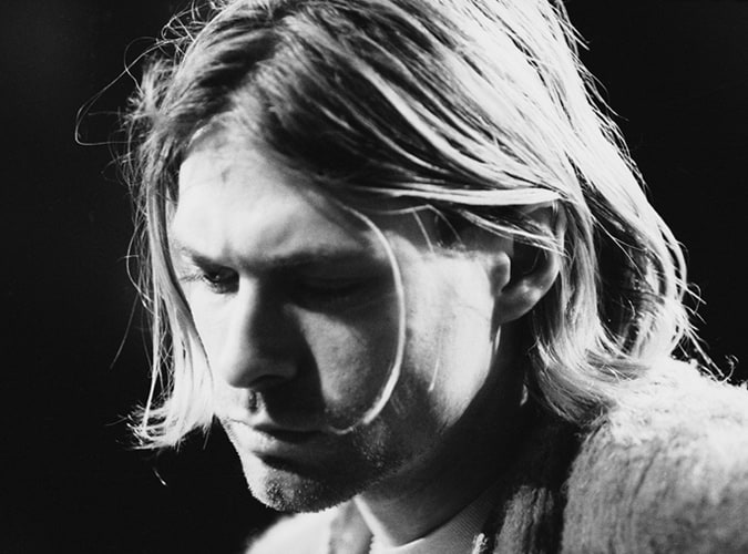 Black and white portrait of a man with a grunge-inspired Eboy haircut, featuring loose, shoulder-length layers and a natural middle part.