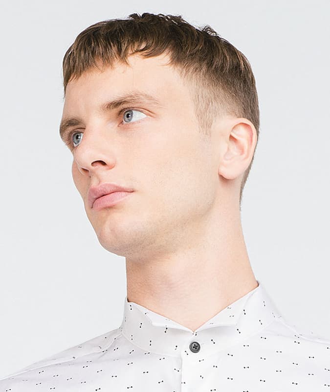 Close-up of a man with a textured drop fade haircut featuring a short fringe and clean taper on the sides.