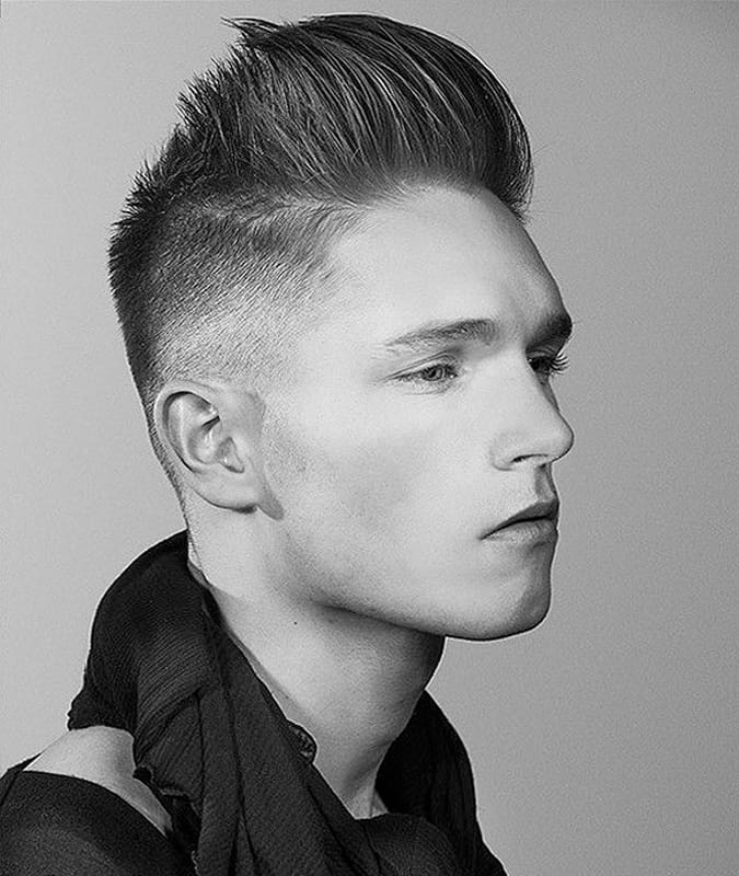 Side profile of a man with a high drop fade haircut and a tall voluminous pompadour.