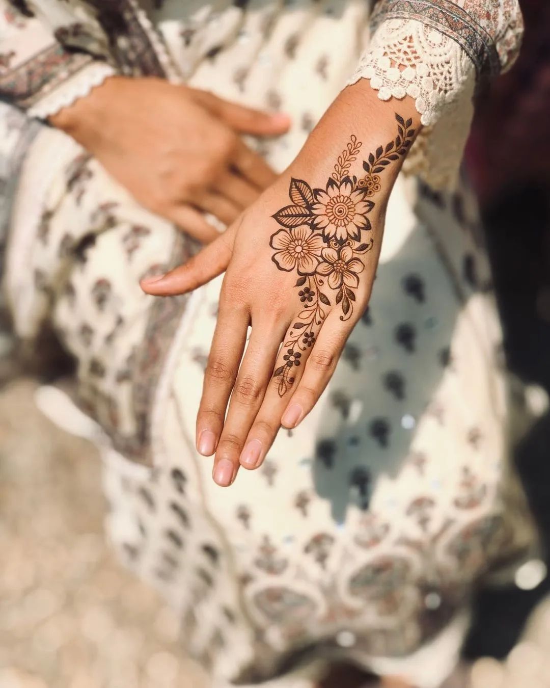 Minimalist floral Mehndi design on the back of the hand with delicate leaf and flower patterns, ideal for casual events