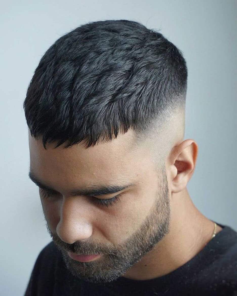 Close-up of a men's textured crop haircut with a high skin fade and short fringe.