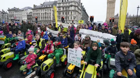 PA Dozens of children sit on toy tractors in central London, at the protest