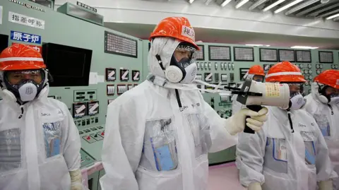 Getty Images A worker measuring radiation levels at the Fukushima Daichi nuclear power station in 2014