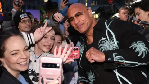 Getty Images Dwayne 'The Rock' Johnson posing for photos with fans