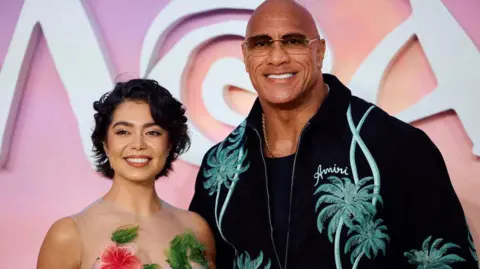 Getty Images US actress Auli'i Cravalho (L) and US actor Dwayne Johnson pose on the red carpet upon arrival for the UK Premier of "Moana 2", at the Cineworld, in Leicester Square, in central London, on November 24, 2024. (