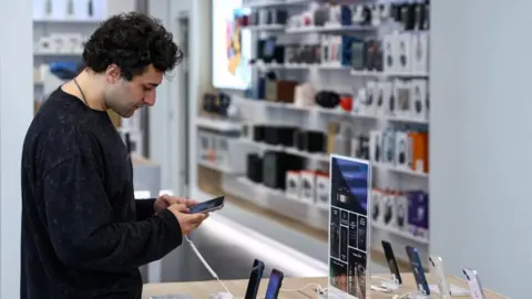 Reuters A man holds an Apple iPhone in a store that sells smartphones 