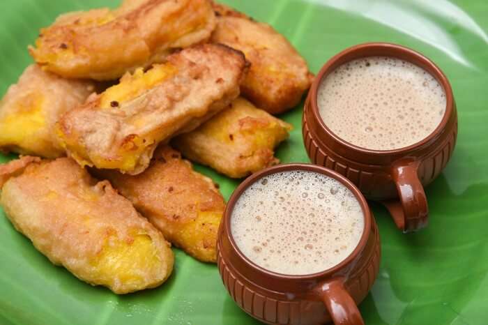 Ethakka Appam, Kerala-style banana fritters, served on a banana leaf with two cups of tea