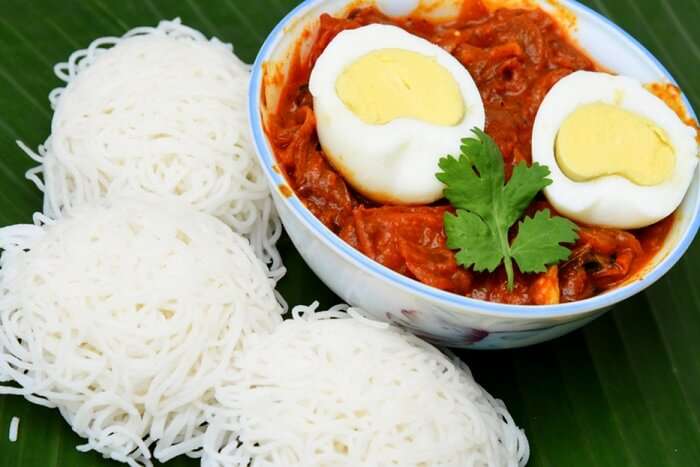 Idiyappam served with a spicy egg curry garnished with boiled eggs and fresh coriander leaves on a banana leaf