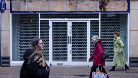 Getty Images A group of women walking in different directions past an empty shop unit on a British High Street in winter