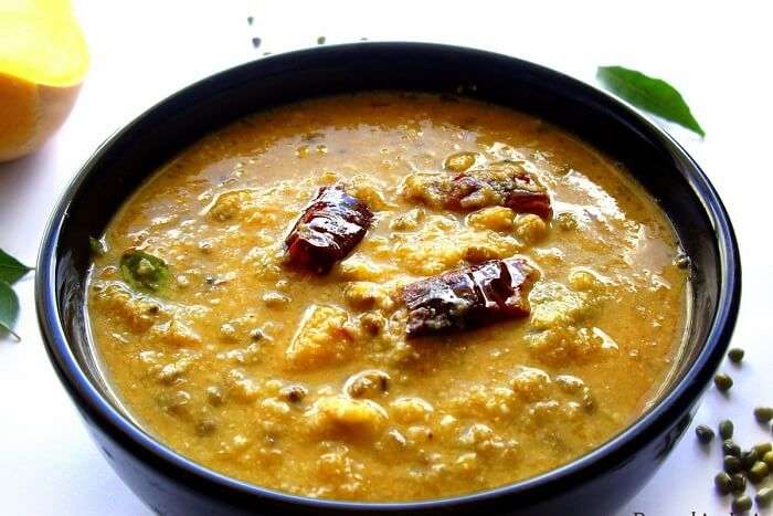 A bowl of Kerala-style Erissery made with pumpkin, lentils, coconut, and garnished with red chilies and curry leaves