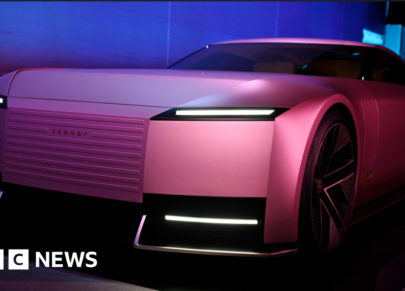 A sleek and futuristic pink Jaguar electric concept car, showcasing bold design and innovative lighting features, under dramatic showroom lighting.